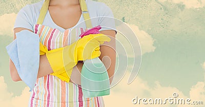 Woman in apron holding spray bottle against sky background Stock Photo