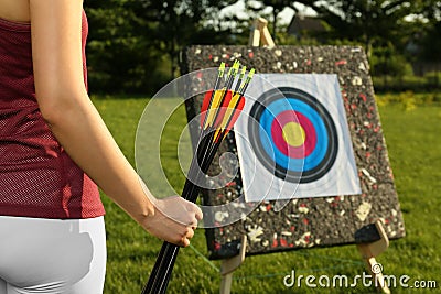 Woman with arrows near archery target in park, closeup Stock Photo