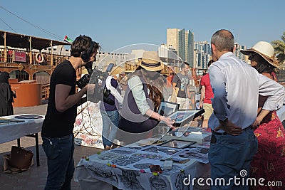 Film crew interviews artists at an outdoor art fair in Dubai, United Arab Emirates Editorial Stock Photo