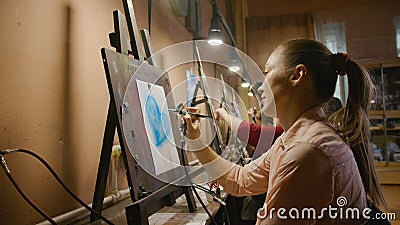 Woman artist learns to paint with airbrush with acrylic dye, paper and easel. Concept modern art, airbrushing Stock Photo