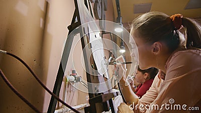 Woman artist learns to paint with airbrush with acrylic dye, paper and easel. Concept modern art, airbrushing Stock Photo
