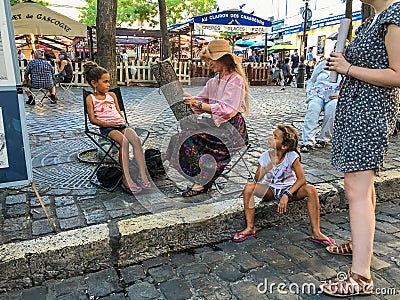 Woman artist paints young girl at Place du Tertre, Montmartre, Paris Editorial Stock Photo