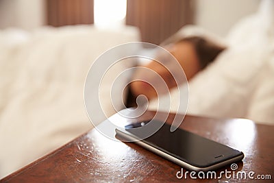 Woman Asleep In Bed With Mobile Phone On Bedside Table Stock Photo