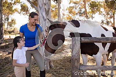 Woman assisting girl for cleaning horse Stock Photo