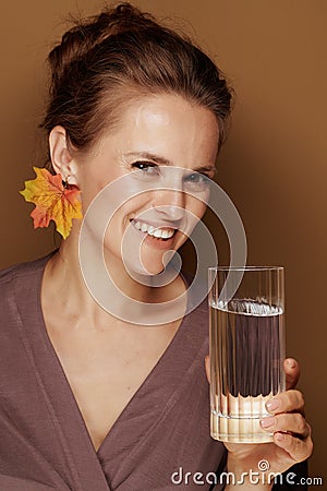 Woman with autumn leaf earring holding glass of water Stock Photo