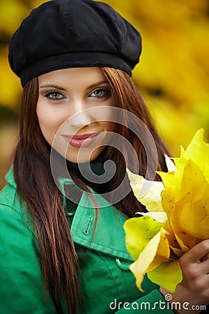 Woman in autumn park holding yellow leaf Stock Photo