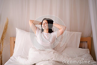 Woman awakening stretching in bed in early morning Stock Photo