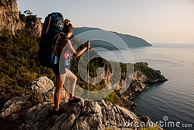 Woman with backpack on top of mountain enjoy view of beautiful sea landscape. Stock Photo