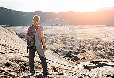 Woman with backpacker enjoying sunrise at desert canyon. Stock Photo