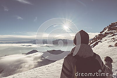 Woman backpacker hiker looking at view high up on the Alps. Rear view, winter cold snow, sun star in backlight, split toning, desa Stock Photo