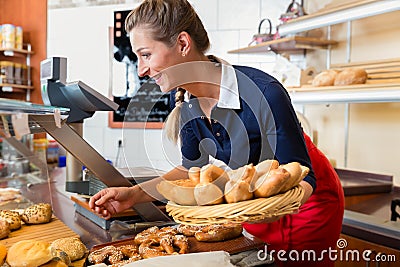 Woman in bakery shop putting bread into display to sell it Stock Photo