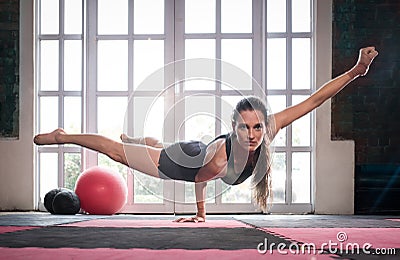 Woman balancing while doing a one hand push up showing strength Stock Photo