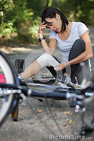 woman bandaging knee after cycling accident Stock Photo