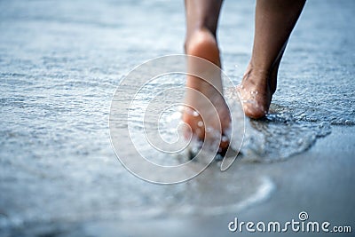 Toe Woman bare foot walking on the summer beach. close up leg of young woman walking along wave of sea water and sand on the beach Stock Photo