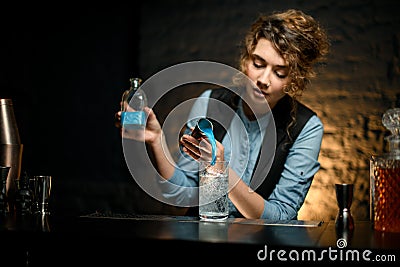 Woman bartender carefully pours drink from jigger into glass of cold water Stock Photo