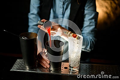Woman bartender gently pours drink from jigger into metal glass Stock Photo