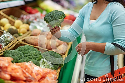 Woman with basket buying broccoli at grocery store Stock Photo