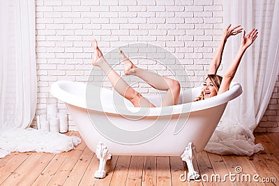 Woman in bath having fun. Beautiful young blonde woman enjoying pleasant bath, looking at camera and smiling Stock Photo