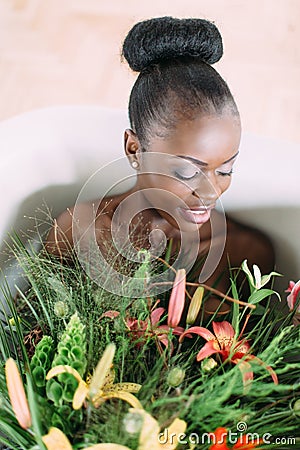 Woman bathing in a tub full of foam. Beautiful african american bride in decorated bath. Beautiful african american Stock Photo