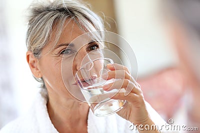 Woman in bathrobe drinking water Stock Photo