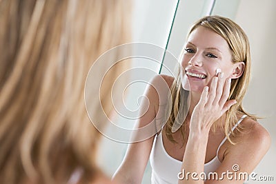 Woman in bathroom applying face cream Stock Photo