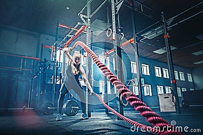 Woman with battle rope battle ropes exercise in the fitness gym. Stock Photo