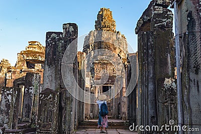 Woman in Bayon Temple looking at stone faces, Angkor Thom, morning light clear blue sky. Buddhism meditation concept, world famous Stock Photo