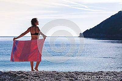 Woman on beach covering hips with towel Stock Photo