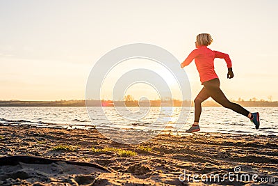Woman beach running at sunrise, lake coastline Stock Photo