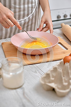 Woman beats eggs in a bowl. housewife cooking on kitchen Stock Photo