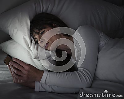 Woman in bed being sentimental on her mobile phone Stock Photo