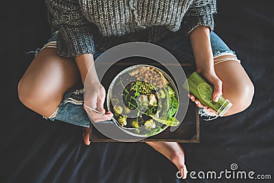 Woman in bed eating vegan dish and drinking smoothie Stock Photo