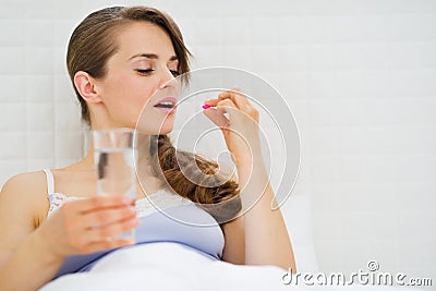 Woman in bed taking pills Stock Photo