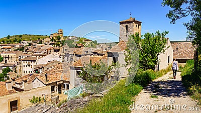 Woman from behind walking along path next to medieval old town. Sepulveda Segovia Editorial Stock Photo