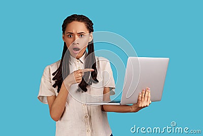 Woman being shocked operational software problems, points of at laptop screen, afraids of data loss. Stock Photo