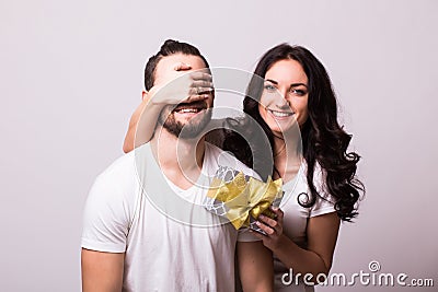 Woman with big toothy smile holding boyfriends eyes giving him a present for Valentine's day. Stock Photo