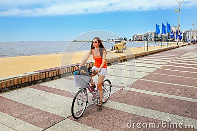 Woman biking on the boulevard along Pocitos beach in Montevideo, Uruguay. Stock Photo