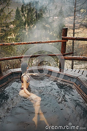 Woman in bikini bathing in Japanese style bath outdoors Stock Photo