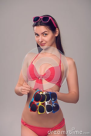 Woman in bikini holding many colourful sunglasses Stock Photo