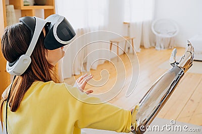 Woman with bionic arm and VR headset plays game in room Stock Photo