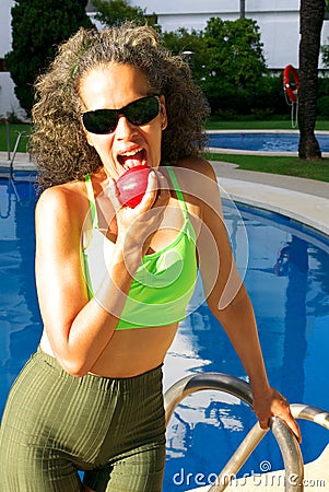 Woman over 50 by the Pool bitting Apple Stock Photo