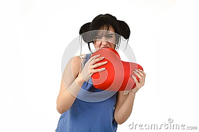 Woman biting in rage spiteful and resentful a red heart shape pillow upset Stock Photo