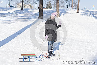 A woman in a black winter jacket with sledges in a snow-covered park or forest Stock Photo