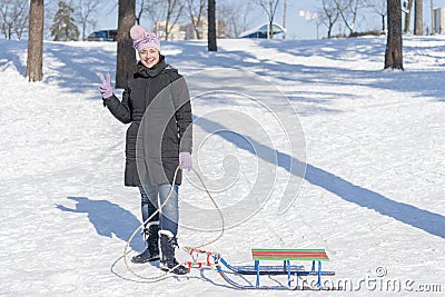 A woman in a black winter jacket with sledges in a snow-covered park or forest Stock Photo