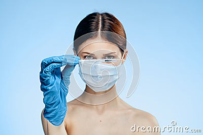 Woman on a blue background in a medical mask holds a syringe, portrait Stock Photo