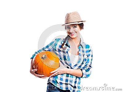 Woman in blue checked shirt, hat holding orange pumpkin Stock Photo