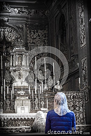 Woman in a blue coat and white veil praying - selective color Editorial Stock Photo