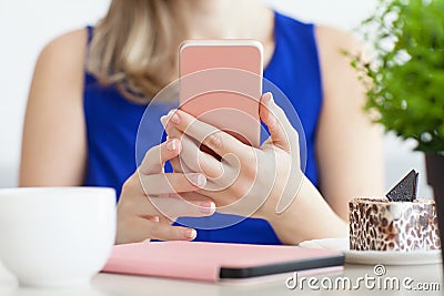 Woman in blue dress in the cafe holding pink phone Stock Photo