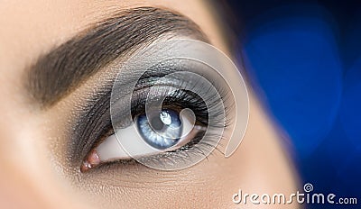 Woman blue eye with perfect makeup. Beautiful professional smokey eyes holiday make-up. Eyebrows shaping, eyes and eyelashes Stock Photo