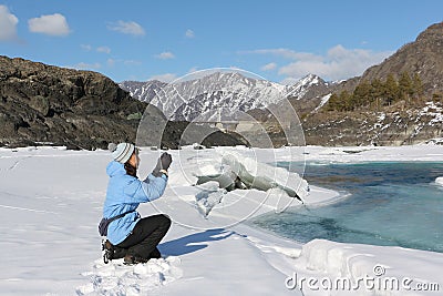 The woman in a blue jacket photographing the thawing river Stock Photo